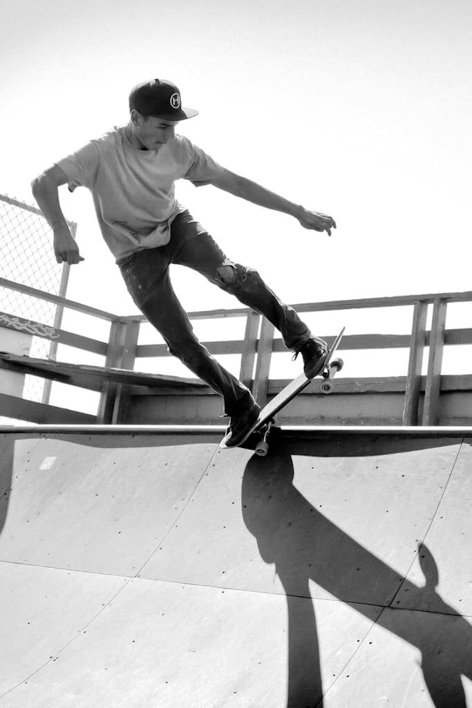 Black and white action shot of a skateboarder performing a trick on a ramp at Cayucos Skate Park.